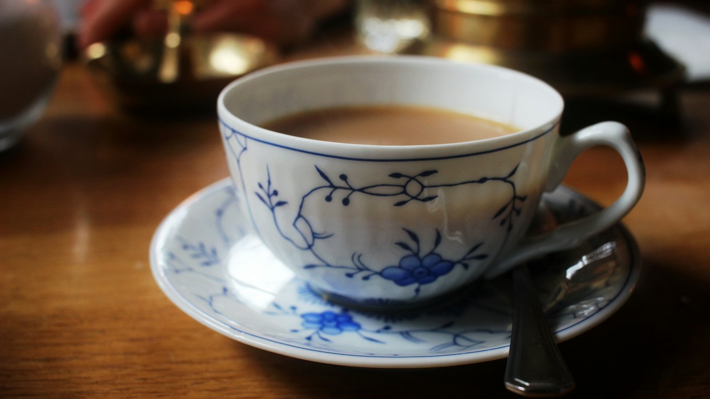 Tazza e piattino fantasia con cucchiaino su legno.