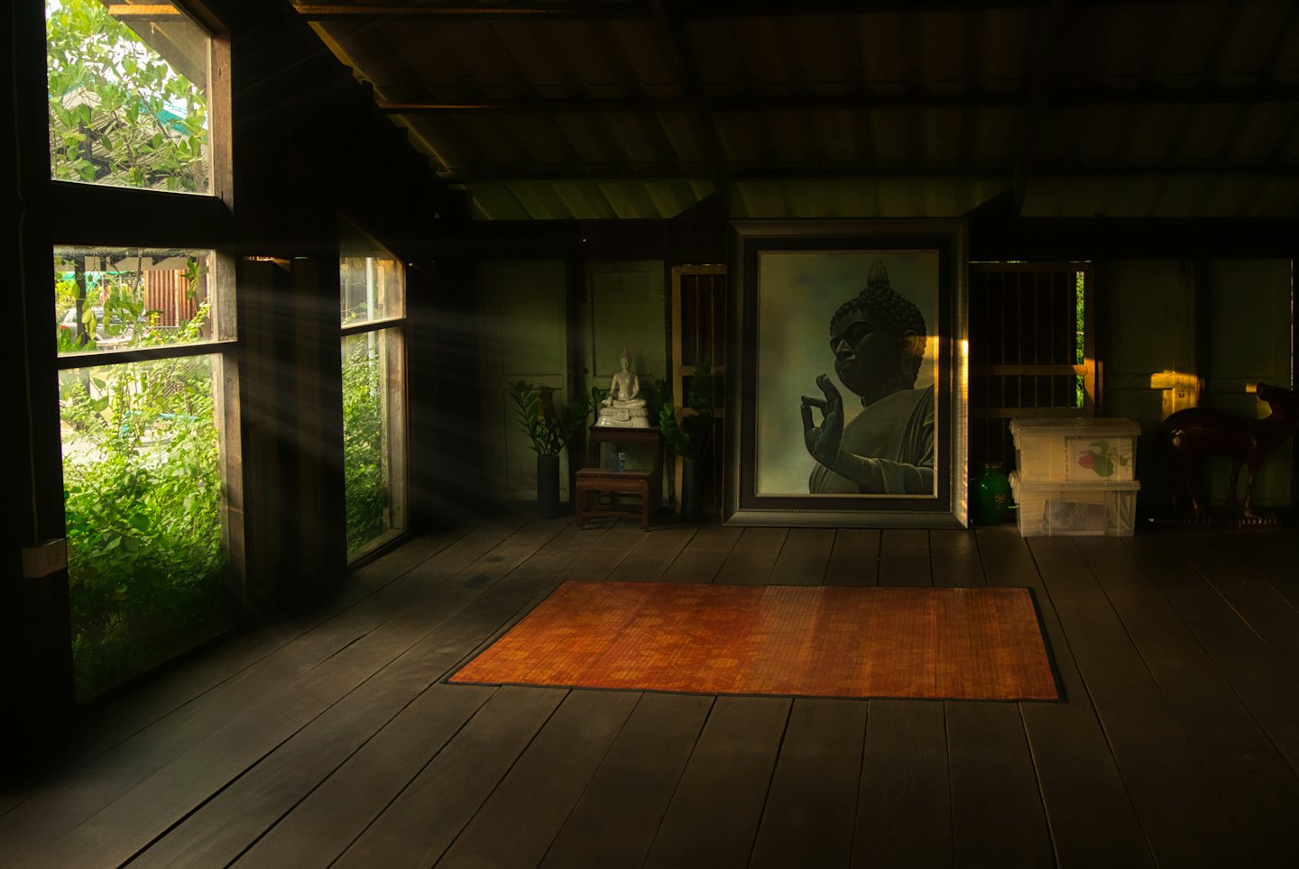 Statua di Buddha e tappetino da meditazione in una stanza illuminata dal sole.