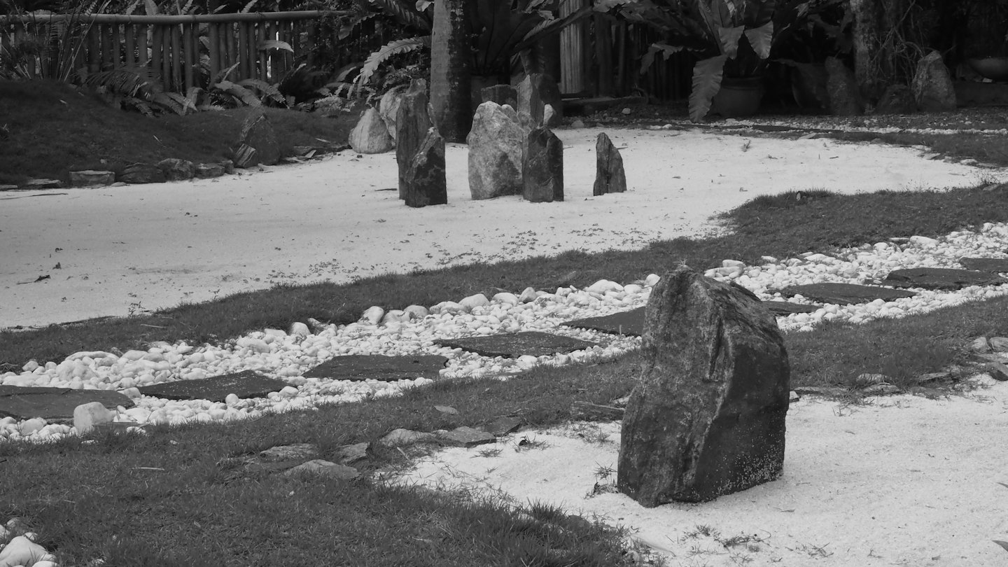 Giardino zen con sabbia rastrellata, ciottoli lisci e pietre per camminare.